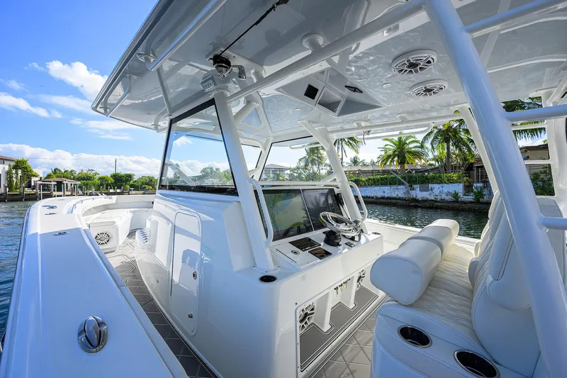Denied Yacht Photos Pics 2021 Yellowfin 42 boat interior with modern helm, white seating, and tropical waterfront view.