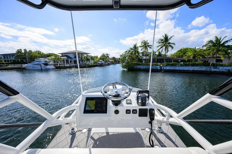 Denied Yacht Photos Pics Cockpit view of 2021 Yellowfin 42 boat navigating a scenic waterway with palm trees.