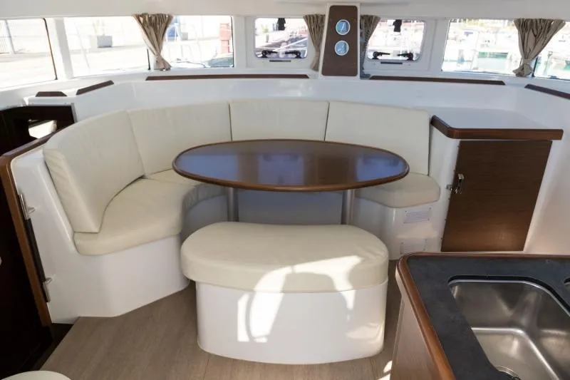  Yacht Photos Pics Interior of 2019 Lagoon 380 catamaran with round table and cushioned seating.