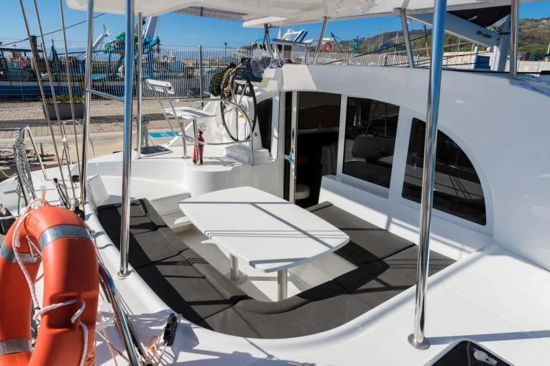  Yacht Photos Pics 2019 Lagoon 380 catamaran with outdoor seating, life preserver, and helm station in a marina.