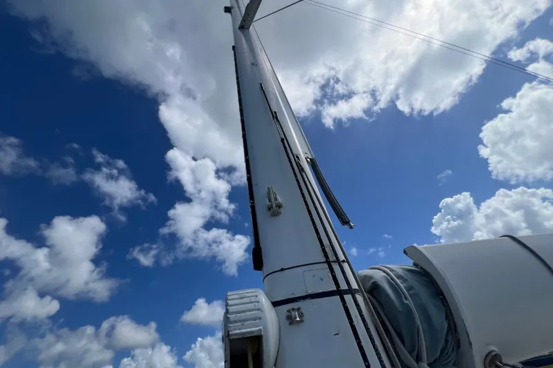 Ibubi Yacht Photos Pics Mast of 2010 Grand Soleil 54 sailboat against a bright blue sky with clouds.