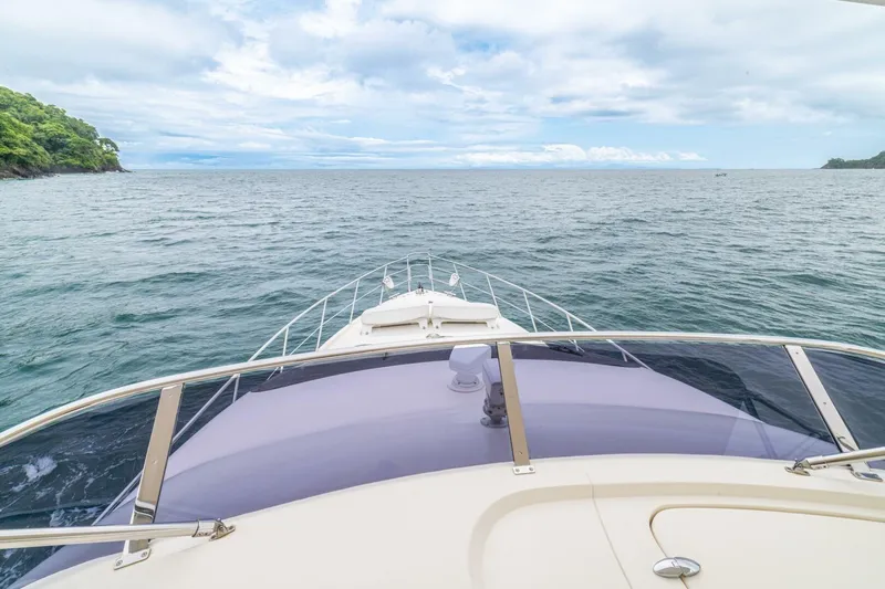 Hakuna Matata Yacht Photos Pics Bow view of 2007 Azimut 55 yacht cruising on open sea with lush coastline.