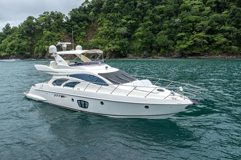 Hakuna Matata Yacht Photos Pics Luxurious 2007 Azimut 55 yacht cruising near lush, green coastline.