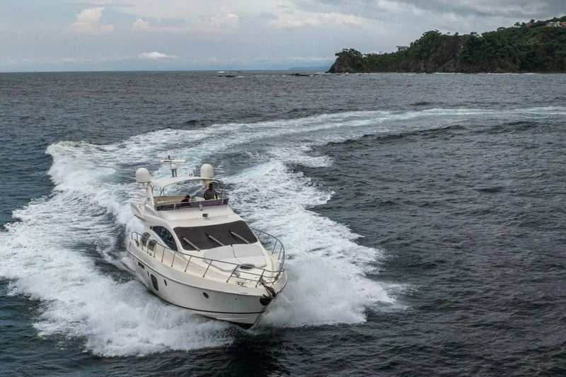 Hakuna Matata Yacht Photos Pics 2007 Azimut 55 yacht cruising on open sea near rocky coastline.