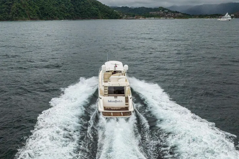 Hakuna Matata Yacht Photos Pics 2007 Azimut 55 yacht cruising on open water with lush green hills in the background.