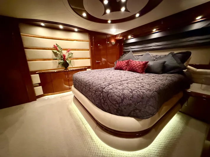 Tenacity Yacht Photos Pics Luxurious bedroom interior of a 2005 Marquis 65 yacht, featuring elegant lighting and plush bedding.
