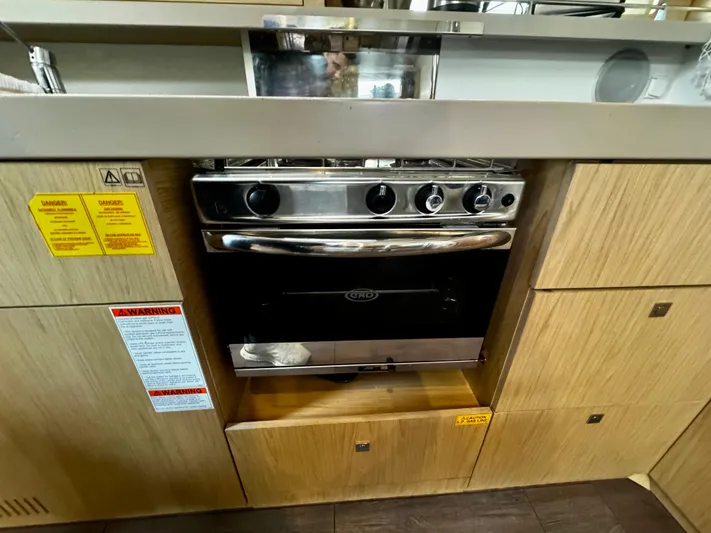  Yacht Photos Pics Beneteau Oceanis 45 (2018) kitchen with stainless steel oven and wooden cabinetry.