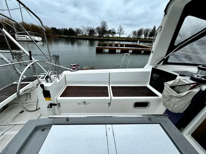  Yacht Photos Pics Cockpit of 2018 Beneteau Oceanis 45 sailboat with wooden seating, docked by a calm lake.