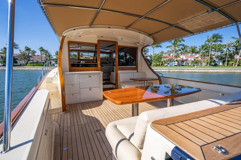 Eleven11 Yacht Photos Pics 2018 Palm Beach Motor Yachts PB55, luxurious deck with elegant seating and table, waterfront view.