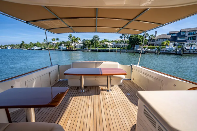 Eleven11 Yacht Photos Pics 2018 Palm Beach Motor Yachts PB55 deck with tables, overlooking serene waterfront.