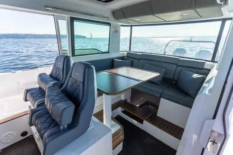  Yacht Photos Pics Interior of 2021 Axopar 37XC Aft Cabin with seating and table, overlooking the ocean.