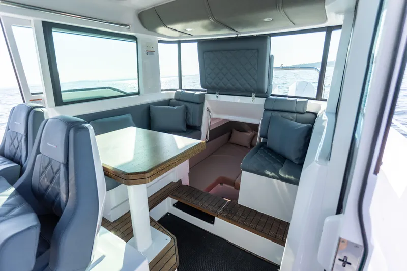  Yacht Photos Pics Interior of 2021 Axopar 37XC Aft Cabin with seating and table, overlooking the sea.