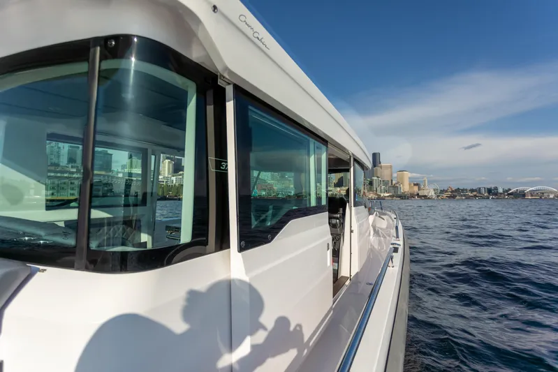  Yacht Photos Pics Axopar 37XC Aft Cabin 2021 cruising near a city skyline on a sunny day.