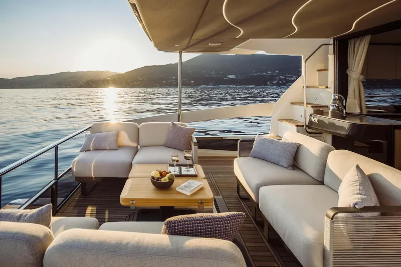  Yacht Photos Pics Luxurious 2025 Absolute 52 FLY yacht deck with elegant seating, overlooking serene waters at sunset.