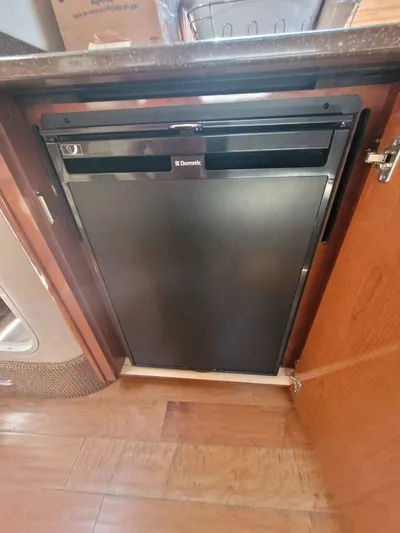 Knot On Call Yacht Photos Pics Compact fridge inside 2013 Sea Ray Sundancer 370 yacht, featuring wooden cabinetry and sleek design.