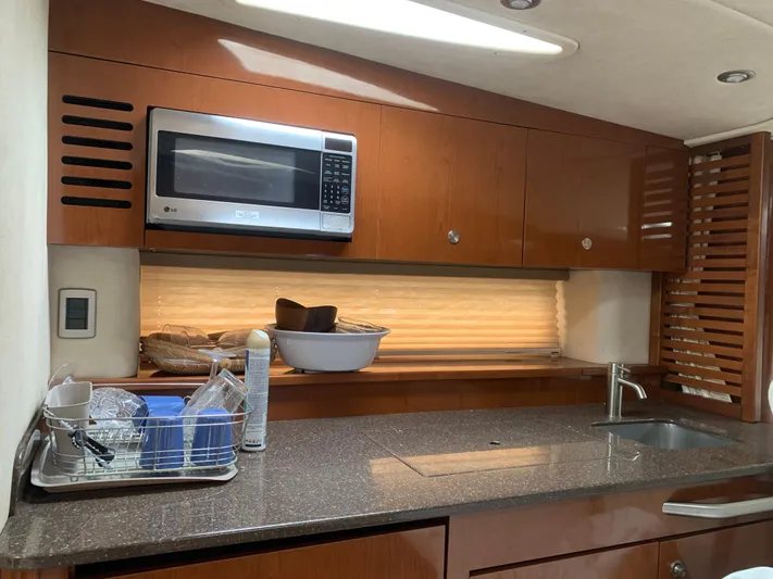 Knot On Call Yacht Photos Pics Kitchen area of 2013 Sea Ray Sundancer 370 with microwave, sink, and wooden cabinets.