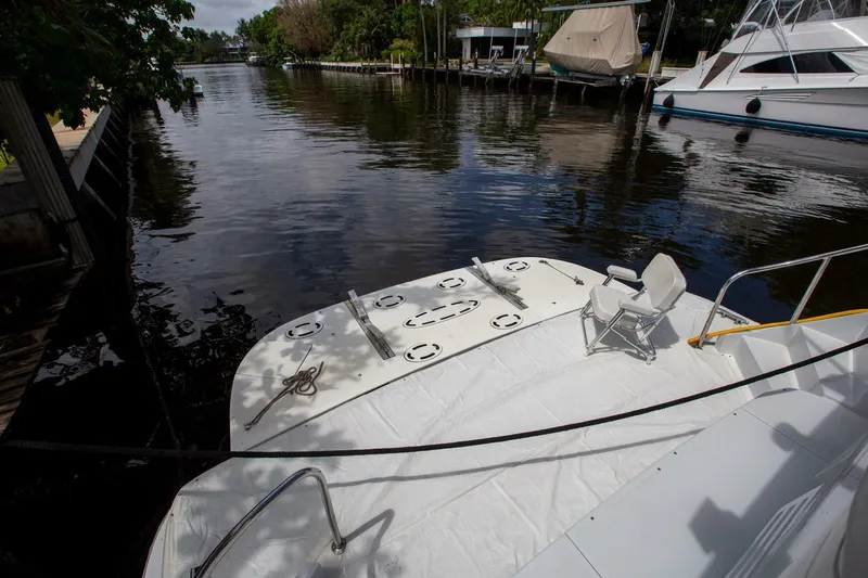 Painkiller Yacht Photos Pics Tarrab 1999 motor yacht docked by a calm river, featuring a spacious deck area.