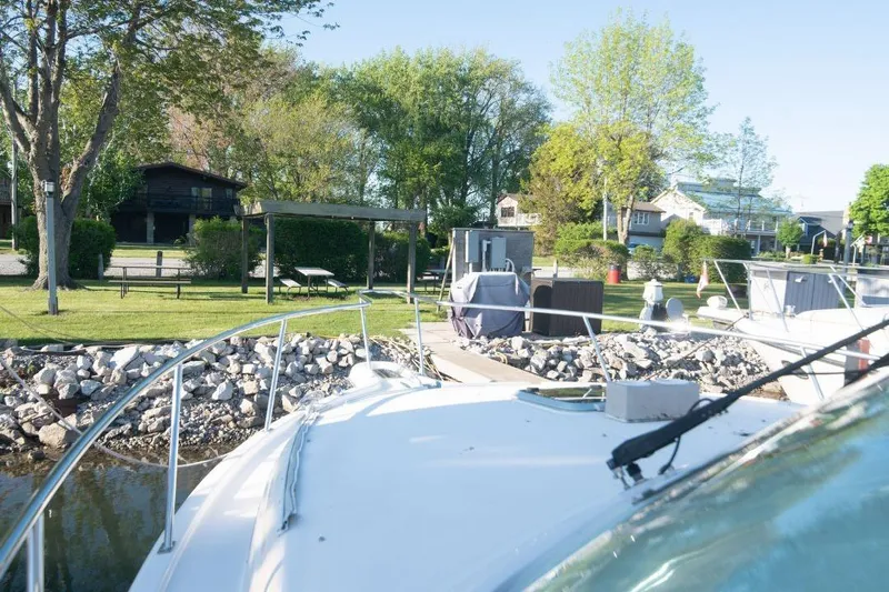  Yacht Photos Pics 2015 Pursuit OS 345 Offshore boat docked near a scenic, tree-lined shore.