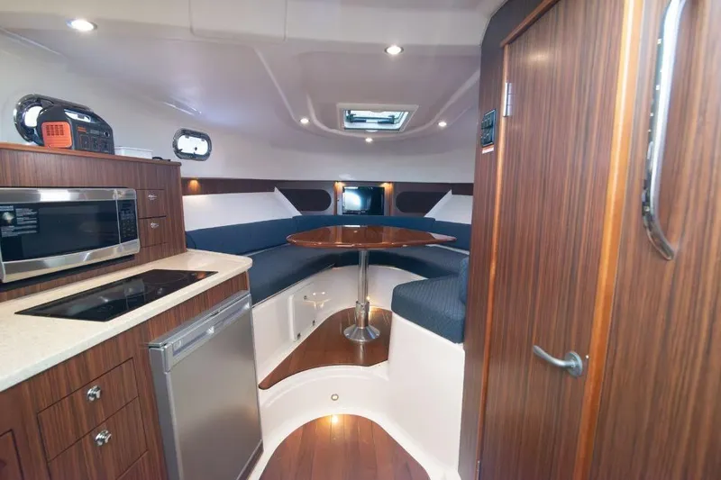  Yacht Photos Pics 2015 Pursuit OS 345 Offshore cabin interior with kitchenette and seating area.