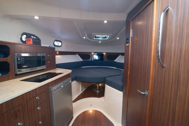  Yacht Photos Pics 2015 Pursuit OS 345 Offshore cabin interior with kitchenette and seating area.