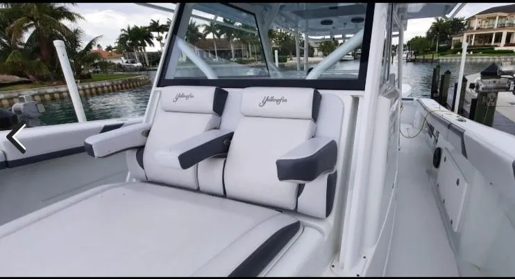 One More Day Yacht Photos Pics 2019 Yellowfin Center Console boat with cushioned seating, docked near palm trees.