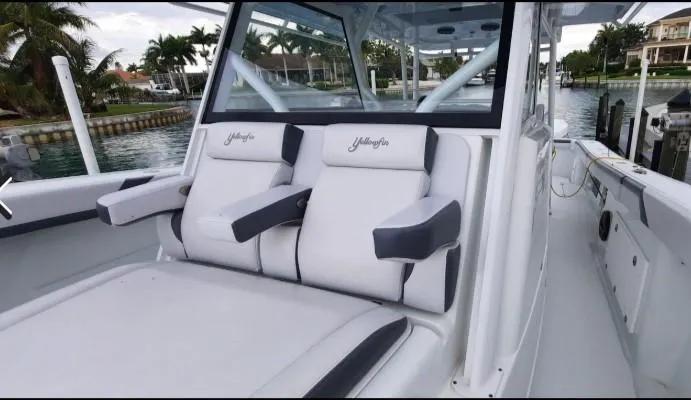 One More Day Yacht Photos Pics 2019 Yellowfin Center Console boat with cushioned seating and armrests, docked by a waterfront.