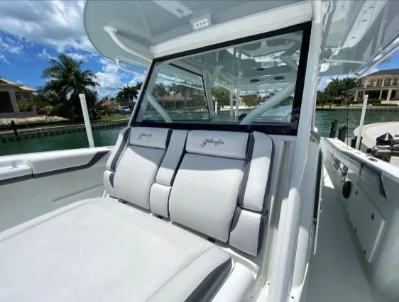 One More Day Yacht Photos Pics 2019 Yellowfin Center Console boat with cushioned seating, docked by a waterfront property.