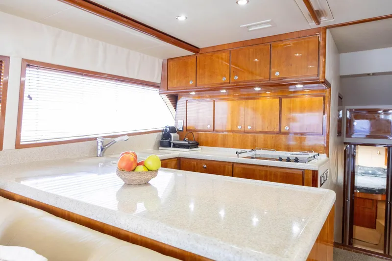 Pecado Yacht Photos Pics Luxurious kitchen interior of 2006 Bertram 510 Convertible yacht with wooden cabinets and countertop.