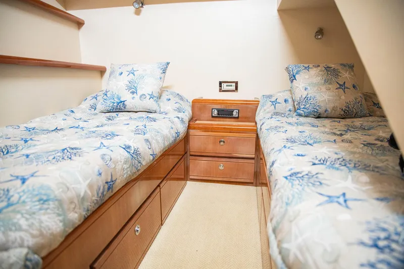 Pecado Yacht Photos Pics 2006 Bertram 510 Convertible cabin with twin beds and nautical-themed bedding.