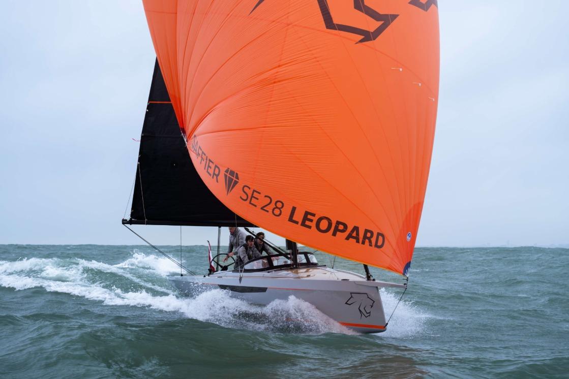 Saffier SE 28 Leopard 2026 sailing with vibrant orange sail on choppy sea.