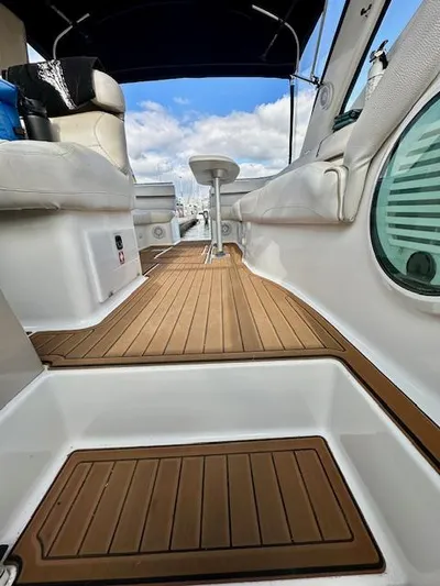 Visionary 21 Yacht Photos Pics 2006 Doral Elegante boat interior with teak flooring and white seating under a blue sky.