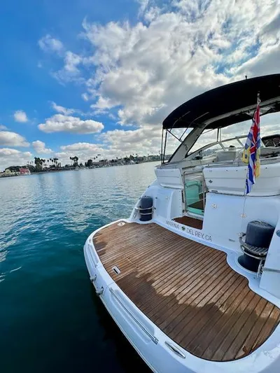 Visionary 21 Yacht Photos Pics 2006 Doral Elegante yacht on calm water, wooden deck, clear sky, and flags displayed.