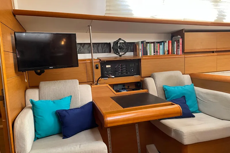 Epicurios Yacht Photos Pics Cozy interior of 2015 Jeanneau Sun Odyssey 469 yacht with seating, TV, and bookshelves.