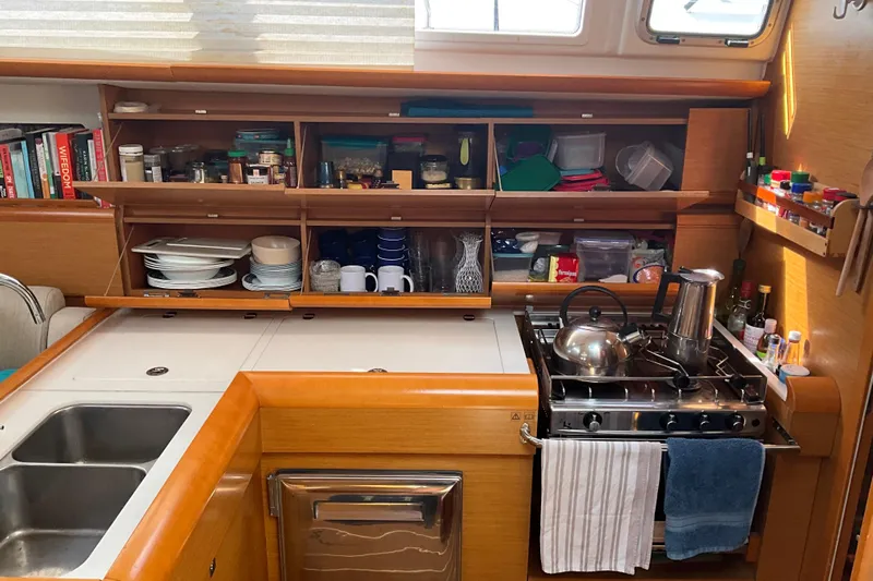 Epicurios Yacht Photos Pics Cozy kitchen in 2015 Jeanneau Sun Odyssey 469 sailboat with stove, sink, and organized shelves.