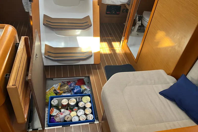 Epicurios Yacht Photos Pics Interior of 2015 Jeanneau Sun Odyssey 469 with storage compartment open, revealing canned goods.