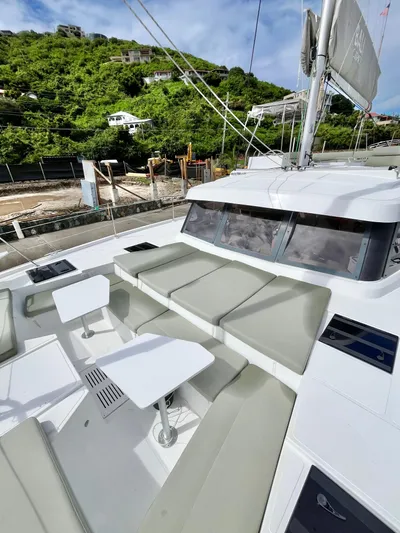 Tropicat Yacht Photos Pics 2024 Bali Catspace 40 yacht with spacious deck and seating, docked near lush green hillside.