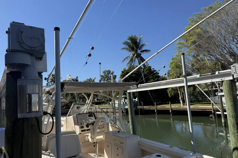 275-264 Brokerage Joe Yacht Photos Pics 2022 Grady-White Freedom 275 boat docked by a scenic canal with palm trees.