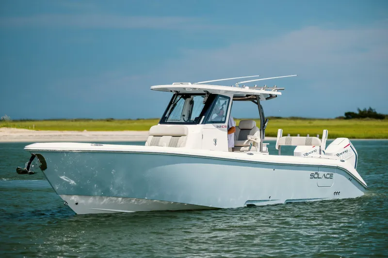  Yacht Photos Pics 2024 Solace 32 CS boat cruising on calm water near a grassy shoreline.
