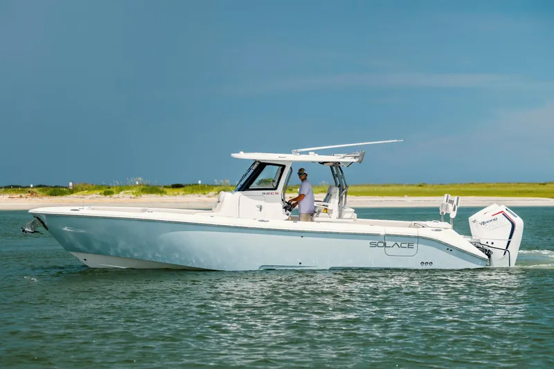  Yacht Photos Pics 2024 Solace 32 CS boat cruising on calm waters near a sandy shoreline.