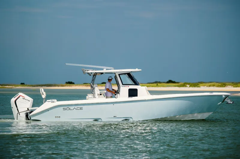  Yacht Photos Pics 2024 Solace 32 CS boat cruising on calm waters near a sandy shoreline.