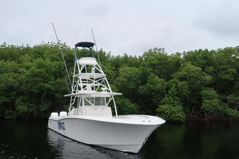 Bad Habit Yacht Photos Pics 2016 Invincible 42 Open Fisherman boat on calm water near lush greenery.