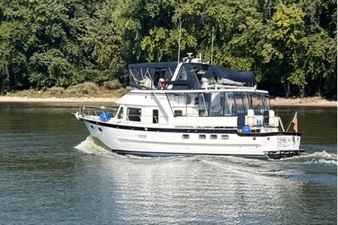 Sea Cow Yacht Photos Pics 2005 DeFever 49 Cockpit Motor Yacht cruising on a calm river with lush green trees.