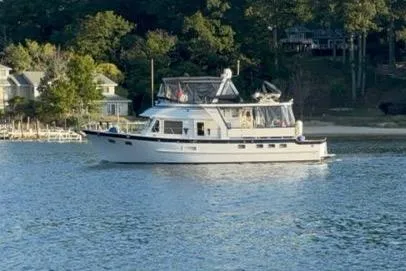 Sea Cow Yacht Photos Pics 2005 DeFever 49 Cockpit Motor Yacht cruising on a serene lake near a wooded shoreline.