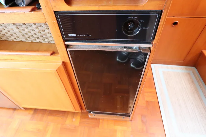 Sea Cow Yacht Photos Pics Built-in trash compactor on 2005 DeFever 49 Cockpit Motor Yacht, featuring wood cabinetry.