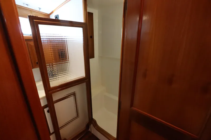 Sea Cow Yacht Photos Pics Interior of 2005 DeFever 49 Cockpit Motor Yacht bathroom with wooden cabinetry and shower.
