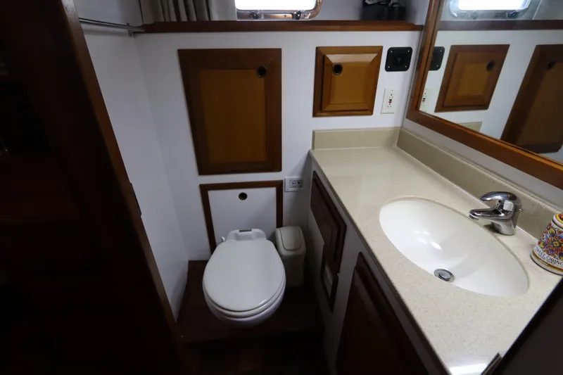 Sea Cow Yacht Photos Pics 2005 DeFever 49 Cockpit Motor Yacht bathroom with sink, toilet, and wooden cabinetry.