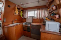 Interior of 2005 Nimbus 380 Commander boat kitchen with wood cabinetry and appliances.