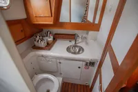 Compact bathroom in a 2005 Nimbus 380 Commander yacht with wooden accents and stainless steel sink.