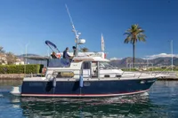 2005 Nimbus 380 Commander yacht cruising near palm trees and mountains.