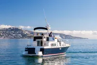 Nimbus 380 Commander 2005 yacht cruising on calm sea with scenic coastal backdrop.